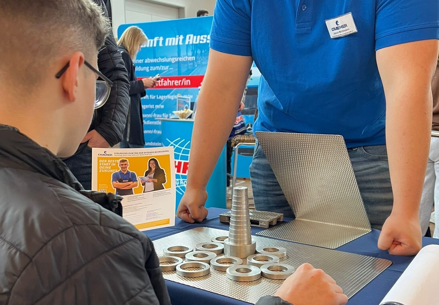 Ein Schüler sitzt am Messestand vor einer Aufgabe mit Metallteilen, die aufzuschichten sind