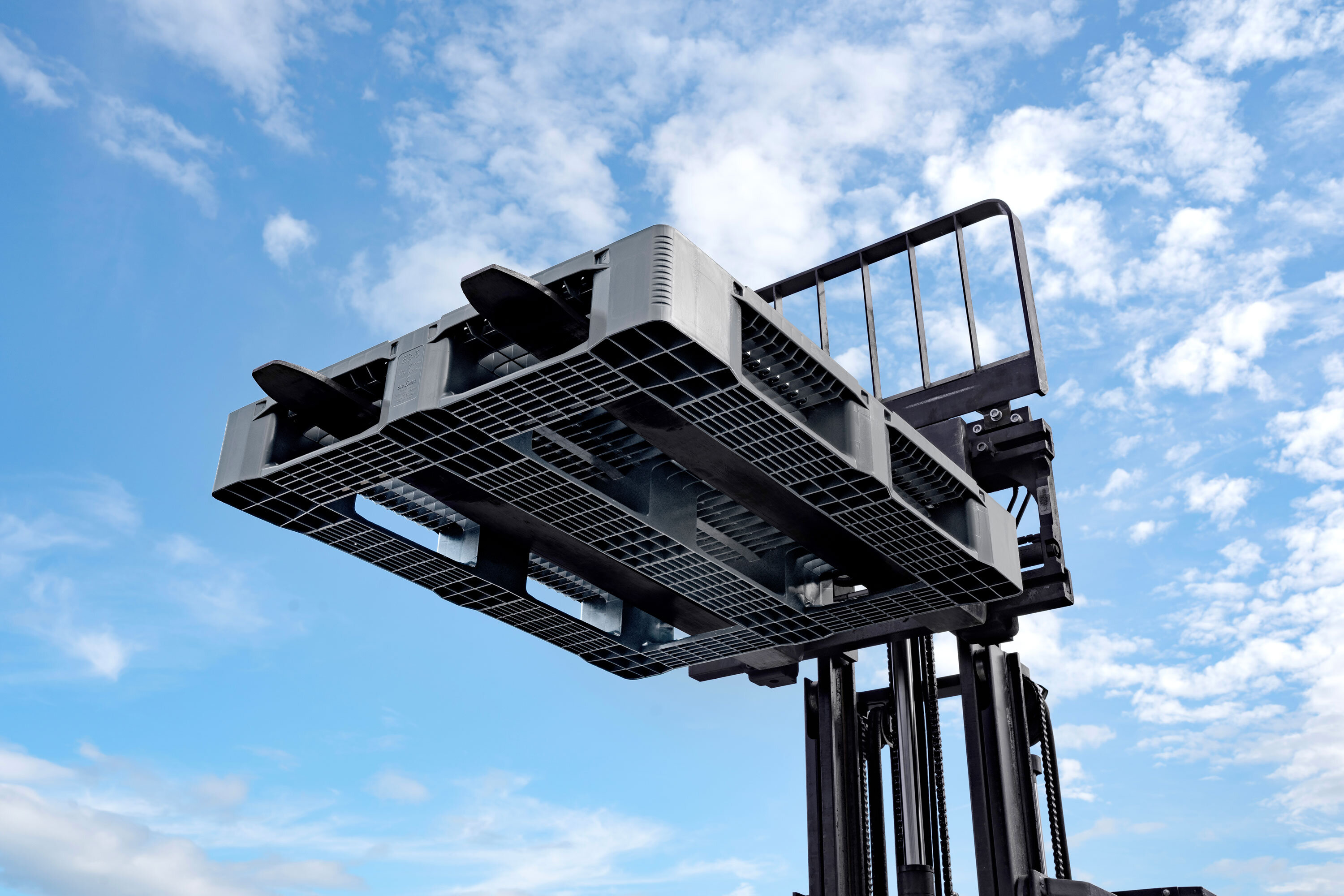 View from the bottom: Basalt grey E3 Plastic Pallet on forklift with blue sky in the background