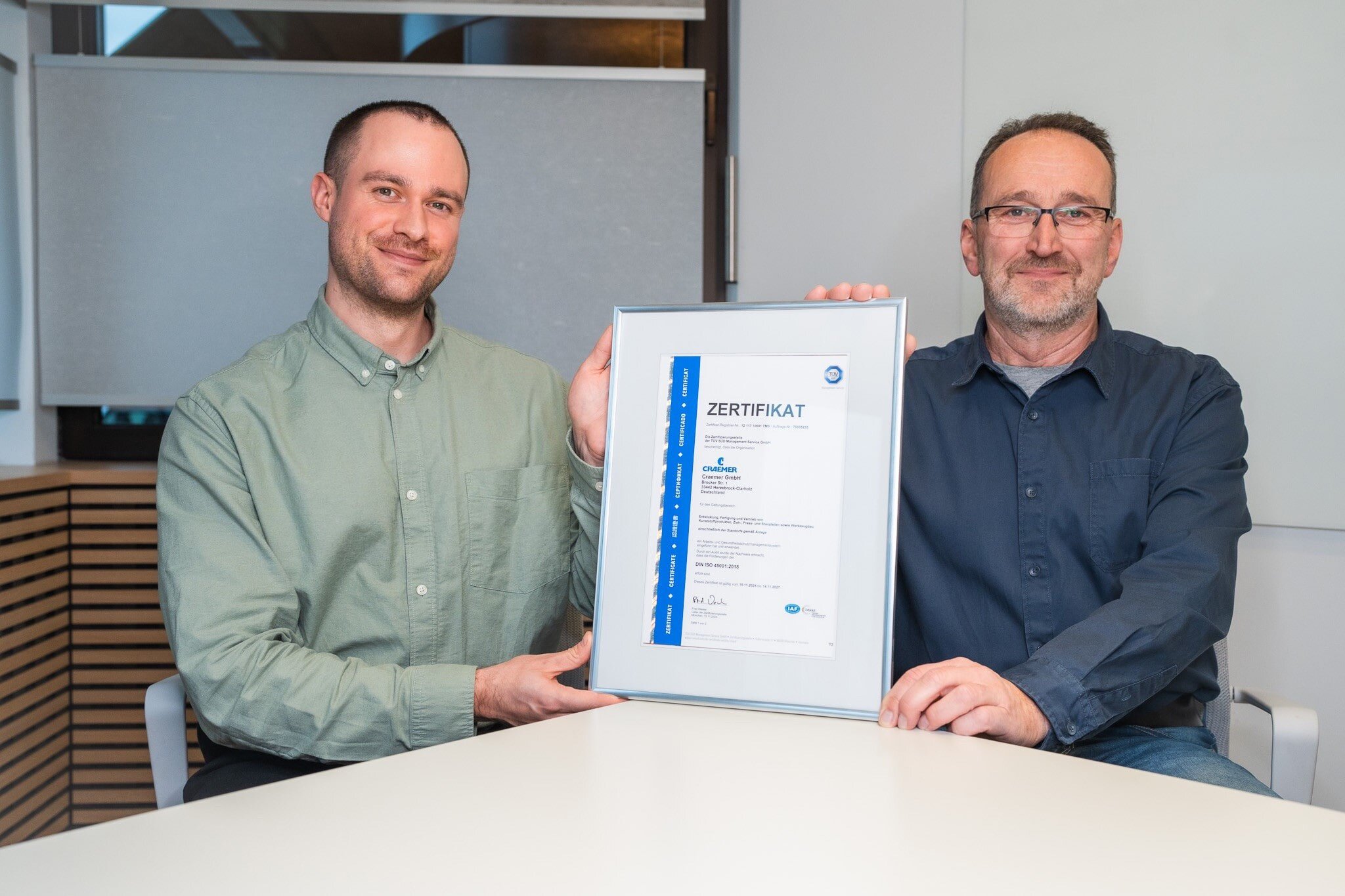 Two persons smiling with certificate