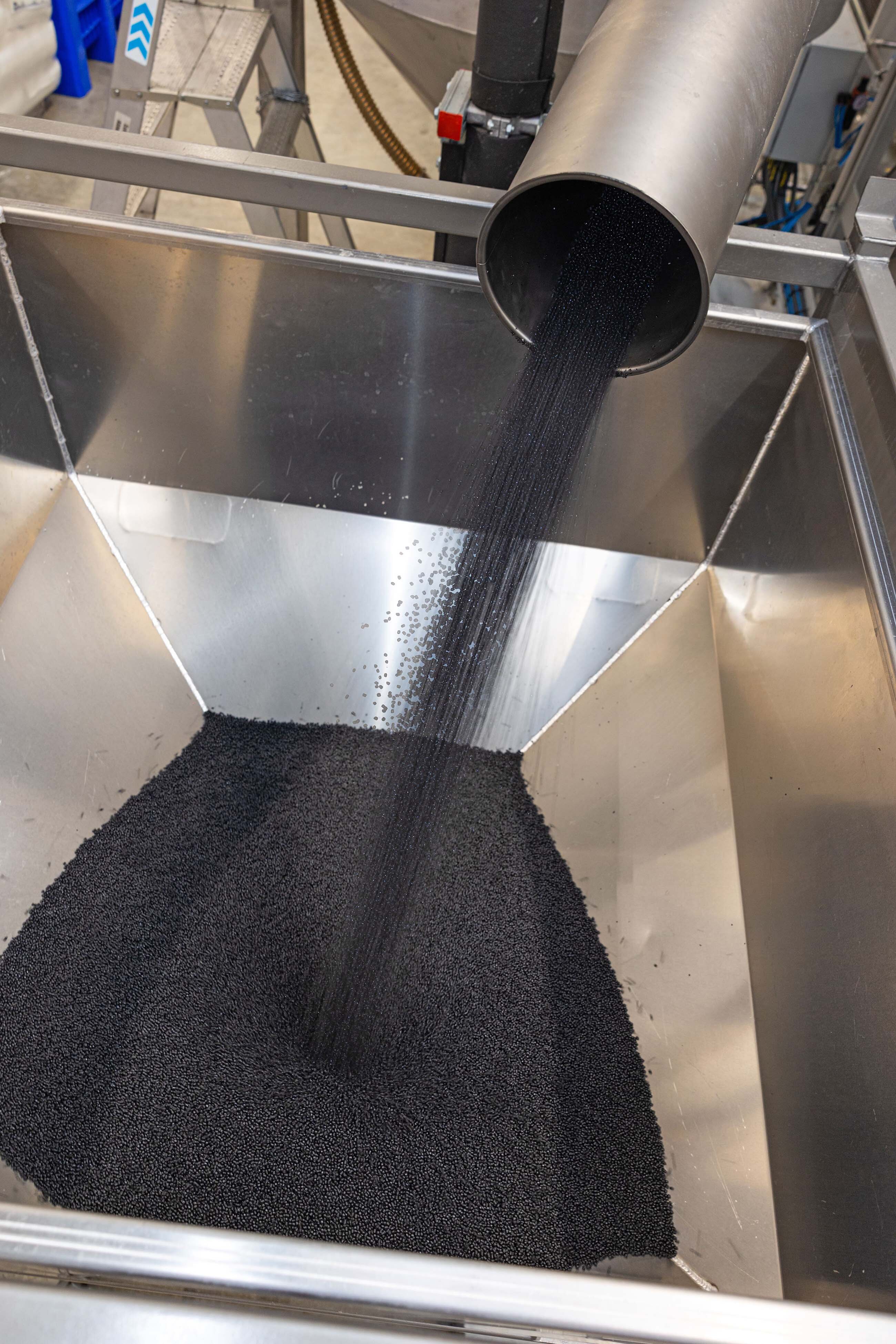 Black regranulate flows into container